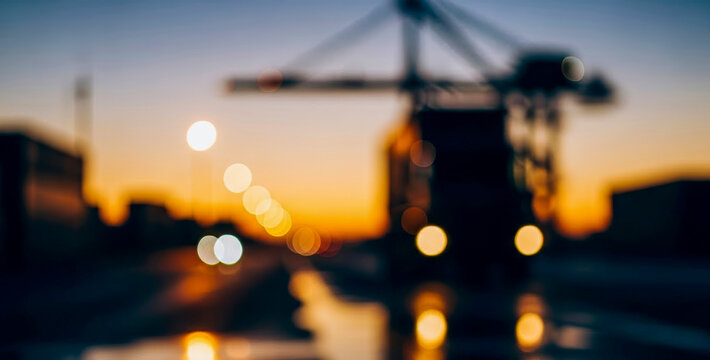 Industrial setting featuring a blurred crane silhouette against a vibrant sunset. Soft bokeh lights create an atmospheric backdrop for this urban landscape. - Powered by Adobe