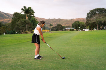 A latin hispanic golfer prepares to swing a golf club on a green course