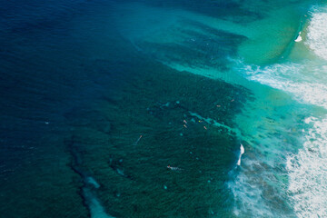 Fototapeta premium Aerial view of reef patterns visible through clear turquoise water at Banzai Pipeline on the North Shore of Hawaii, showing underwater textures and tropical coastline detail.