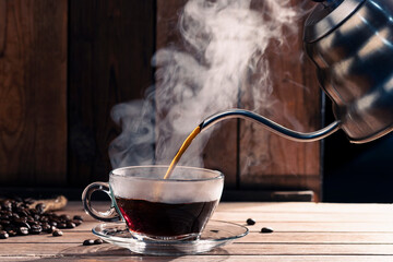 Pour black coffee into a coffee cup There are roasted coffee beans on the table. with a black background and dark colors