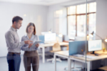 Blurred colleagues collaborating on a tablet in a modern office