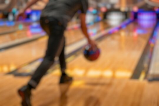 Blurred players aim for that perfect strike. Bowling brings excitement to any leisure night, rolling balls and falling pins fills the air as players in a game of bowling