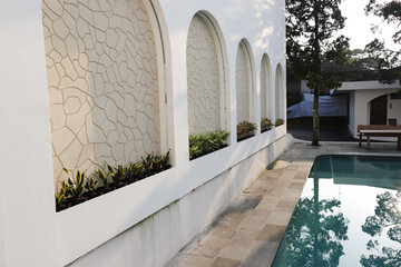 A white building with a pool and a wall of arched windows