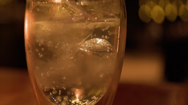 Close Up of Sparkling Drink with Ice in Warm Candlelight