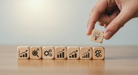 Innovation Initiative: A hand carefully places an icon of a lightbulb representing an idea, adding it to a line of other wooden blocks with growth concept, signaling creativity, innovation.