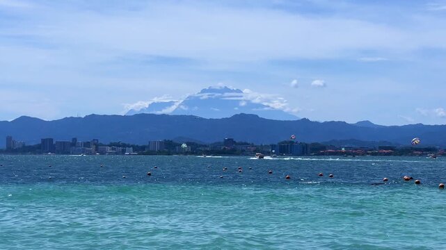 A picturesque view of Mamutik Island Beach, located in Kota Kinabalu, Sabah, Malaysia. View of Mount Kinabalu from the sea. The majestic Mount Kinabalu with clouds in the sky, Borneo. 4К
