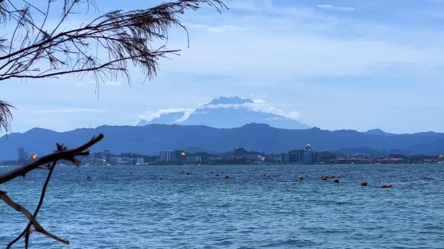 A picturesque view of Mamutik Island Beach, located in Kota Kinabalu, Sabah, Malaysia. View of Mount Kinabalu from the sea. The majestic Mount Kinabalu with clouds in the sky, Borneo. 4К