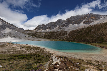 Naklejka premium Turquoise Alpine Lake Beneath Snowy Mountain Peaks