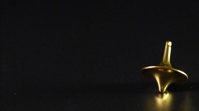 Close Up Shot of a Golden Spinning Top on Black Surface