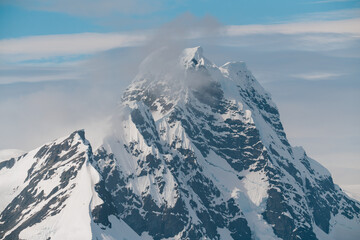 Antarctica Stunning Mountain Peak Covered in Snow and a Lone Cloud with Blue Skies. Close Up of...