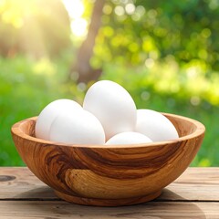 Bowl of white eggs on a wooden surface with a blurred green background and sunlight
