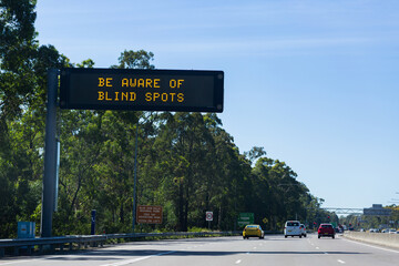 be aware of blind spots warning on digital signage above highway road
