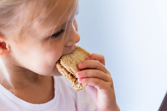 Child eating a vegemite sandwich cut in square