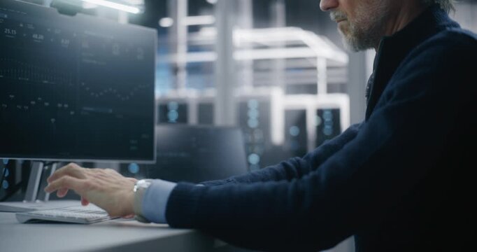 Mature Manager in Formal Attire and Glasses Using Workstation in High Security Modern Data Center. Working in Corporate IT Environment. Concept of Corporate Control and Serious IT Responsibilities.