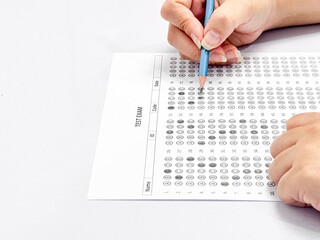 Student hand holding pencil filling out multiple choice answer sheet.1