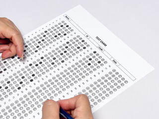 Student hand holding pencil filling out multiple choice answer sheet.1