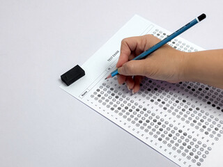 Student hand holding pencil filling out multiple choice answer sheet.1