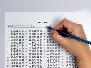 Student hand holding pencil filling out multiple choice answer sheet.1