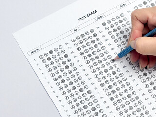 Student hand holding pencil filling out multiple choice answer sheet.1