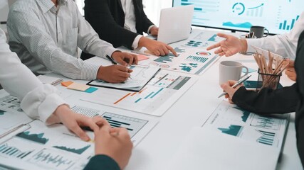 A diverse team engages in a productive meeting, analyzing financial charts and data to strategize for future growth in a modern office setting. SACTR - Powered by Adobe