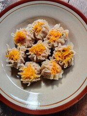 Dimsum with carrot topping on a brown ceramic plate