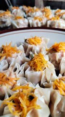 Dimsum with carrot topping on a brown ceramic plate