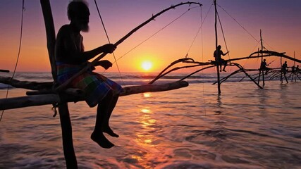 Cinematic slow-motion footage of traditional Sri Lankan stilt fisherman balancing on wooden poles during a vibrant golden sunset on the tropical Indian Ocean coast with crashing waves