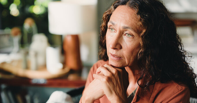 Reflection, nostalgia and mature woman in house with thoughts, past memory and sadness in living room. Mindset, space or senior person in home with perspective, wondering and loss in flashback.