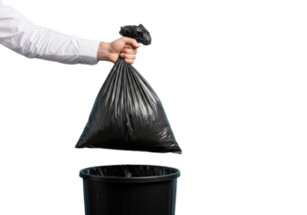 A human hand in a white long-sleeve shirt grips a black garbage bag over a black trash can on a plain light blue background with copy space, bright studio lighting, clean waste disposal concept