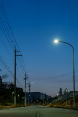 Obraz premium 夕暮れの空を背景にした街灯と送電線の風景