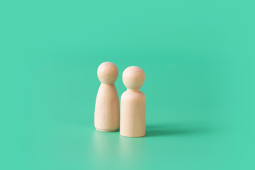 A pair of minimal style female and male wooden figurine on green background.