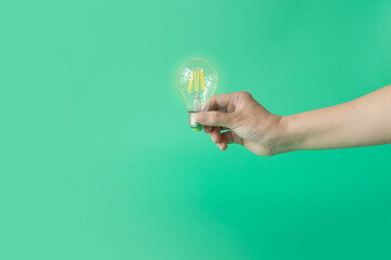 Hand holding a led light bulb on green background.