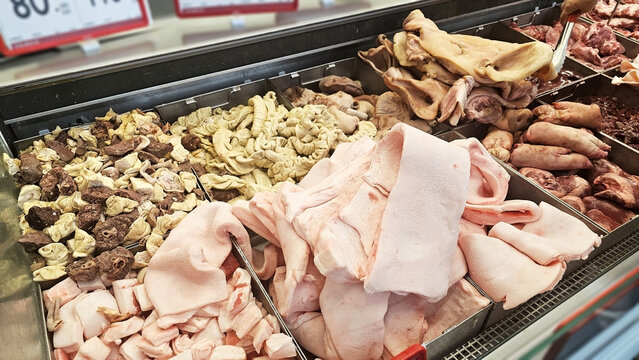 Assorted Butcher's Cuts: A display of various meat products, including different cuts and organ meats, arranged neatly in a refrigerated section of a store.