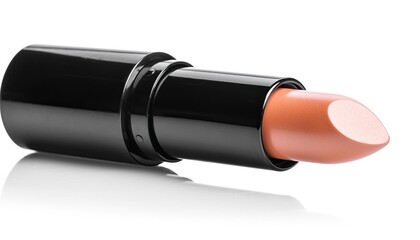 Close-up of a nude lipstick tube with reflection on white surface