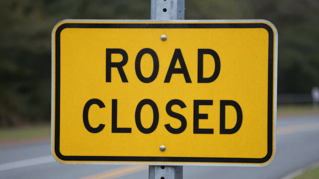 Road closed yellow warning sign on street indicating complete block due to transport hazard or work