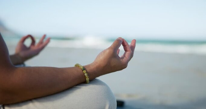 Person, hands and beach with meditation for spiritual wellness, chakra or zen on ocean coast. Closeup, yoga or inner peace with lotus pose, mudra or mantra for mindfulness or calm balance on space