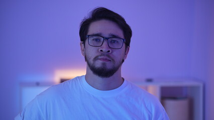 Obraz premium Serious young man in glasses under purple neon light, gamer or programmer portrait.