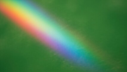 Fototapeta premium Colorful rainbow spectrum on green background. Abstract light refraction pattern for art display or St. Patrick Day festive theme.