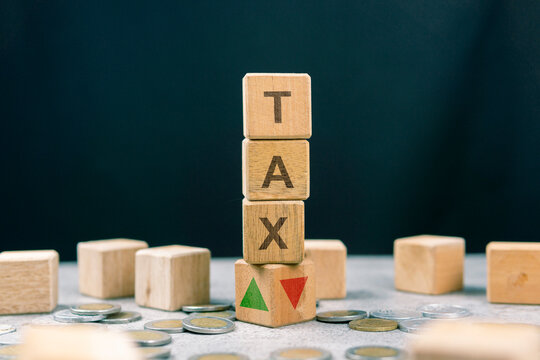 Stack of wooden cubes with the word Tax and arrows pointing up and down. Trends in tax rate changes (up or down). Business and financial tax concepts. Tax rates, percentages, and calculation concepts.