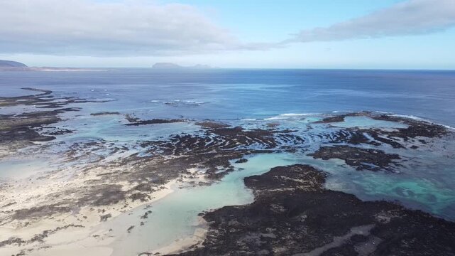Aerial view of volcanic rock pools along rugged coastline