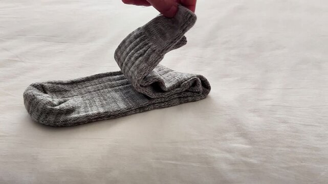 A pair of folded gray ribbed socks rests on a soft light fabric surface, showcasing cozy texture, neutral tones, and a simple setup ideal for clothing, laundry, or lifestyle themes