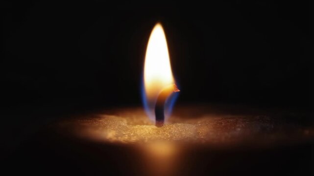 A close-up of a single candle flame burning steadily in the dark. The warm light creates a peaceful and serene atmosphere.