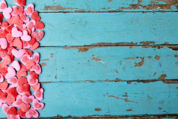 Overhead view of sweet pink and red heart shape candies on blue wooden table with copy space