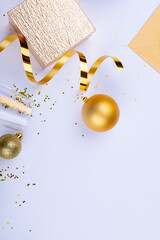 Golden ribbon and baubles by gift box and champagne flute with confetti on white background