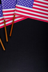 Red and white stripes along with stars on usa flag sticks by copy space on black background