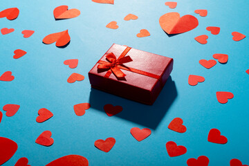 High angle view of red hearts with gift box on blue background, copy space