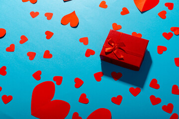 Directly above shot of red hearts with gift box over blue background, copy space