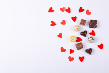 Overhead view of heart shaped decoration and chocolates with copy space over white background