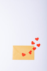 Overhead view of red hearts coming out from yellow envelope with copy space over white background
