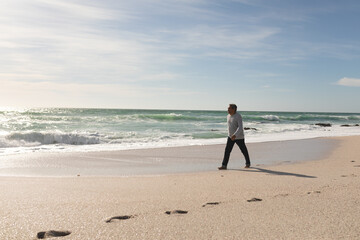 Full length of senior retired man walking on shore at beach against sky during sunny day